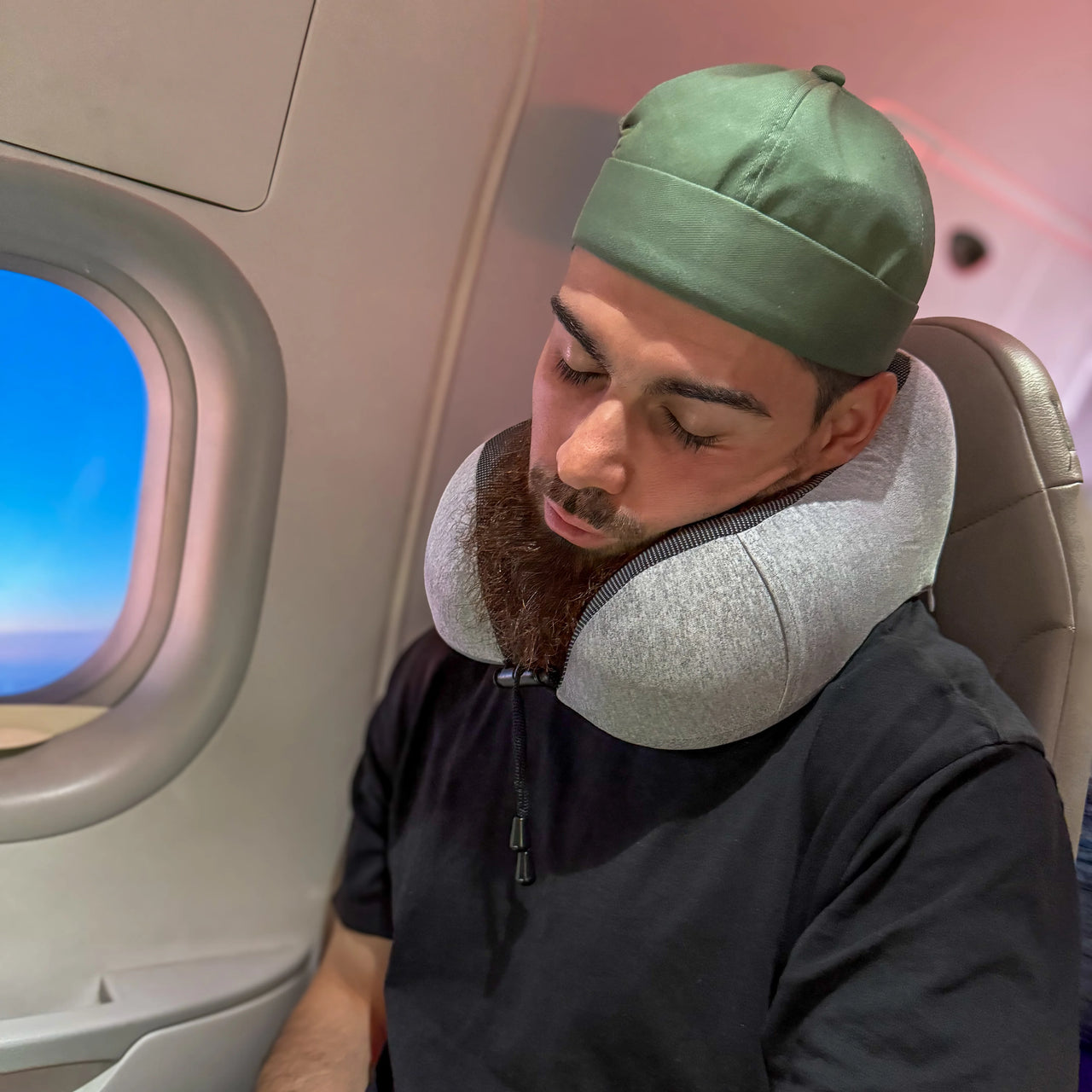 Voyageur profitant d’un coussin de voyage ergonomique gris clair glacé pour un confort cervical optimal en avion. Accessoire léger, compact et pratique pour les longs trajets.