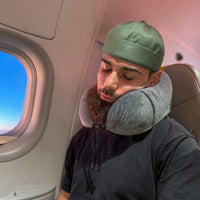 Thumbnail for Personne utilisant un coussin de voyage ergonomique gris anthracite dans un avion pour un soutien cervical optimal. Accessoire confortable et pratique pour les longs trajets.