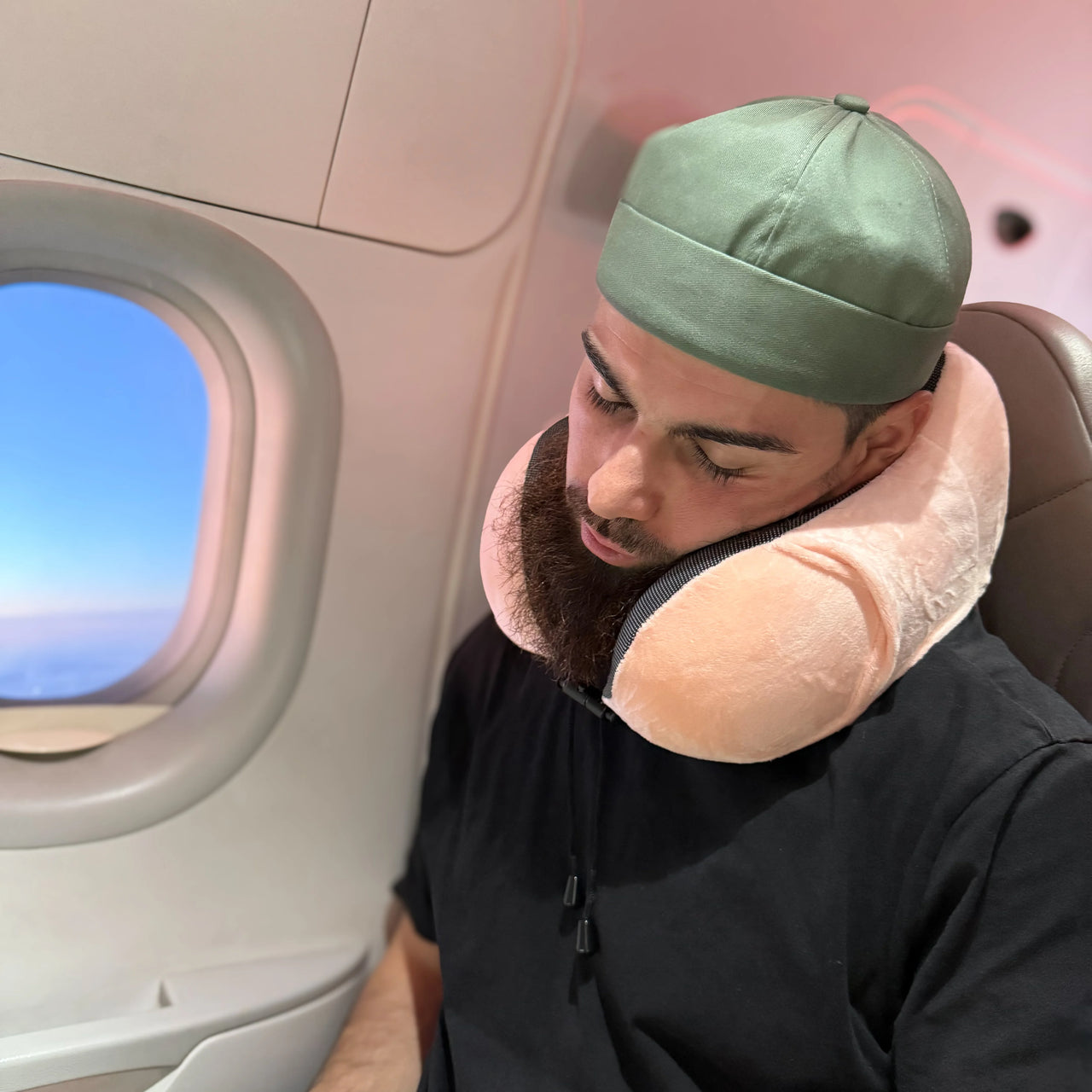 Voyageur utilisant un coussin de voyage ergonomique rose pour un confort cervical optimal en avion. Accessoire doux, compact et parfait pour les trajets longs.