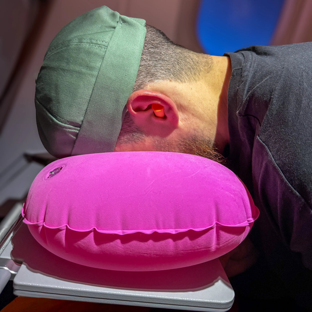 Voyageur utilisant un coussin de voyage gonflable rose pour un soutien ergonomique, idéal pour les longs trajets en avion. Confort et praticité avec gonflage manuel rapide.